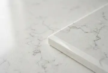 The polished edge of a white engineered quartz slab with grey veining